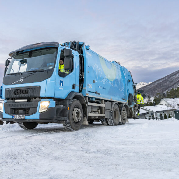 Renovasjonsbil med sjåfør og mann bakpå i vinterlandskap