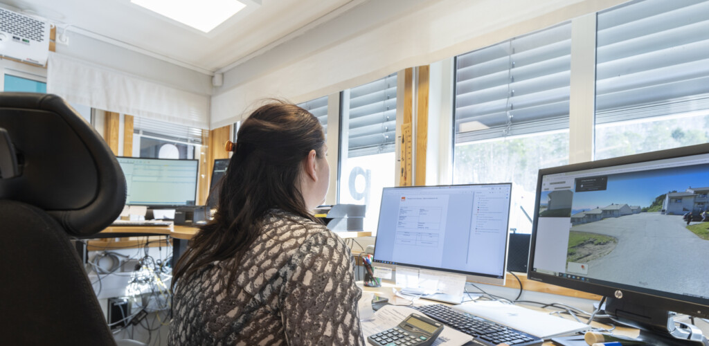 Ansatt som ser på skjermer, med flere skjermer i bakgrunnen