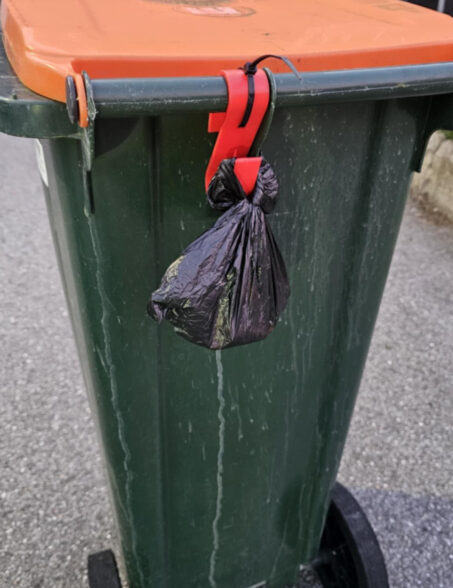 Svart og ikke gjennomsiktig pose som henger på avfallsdunk